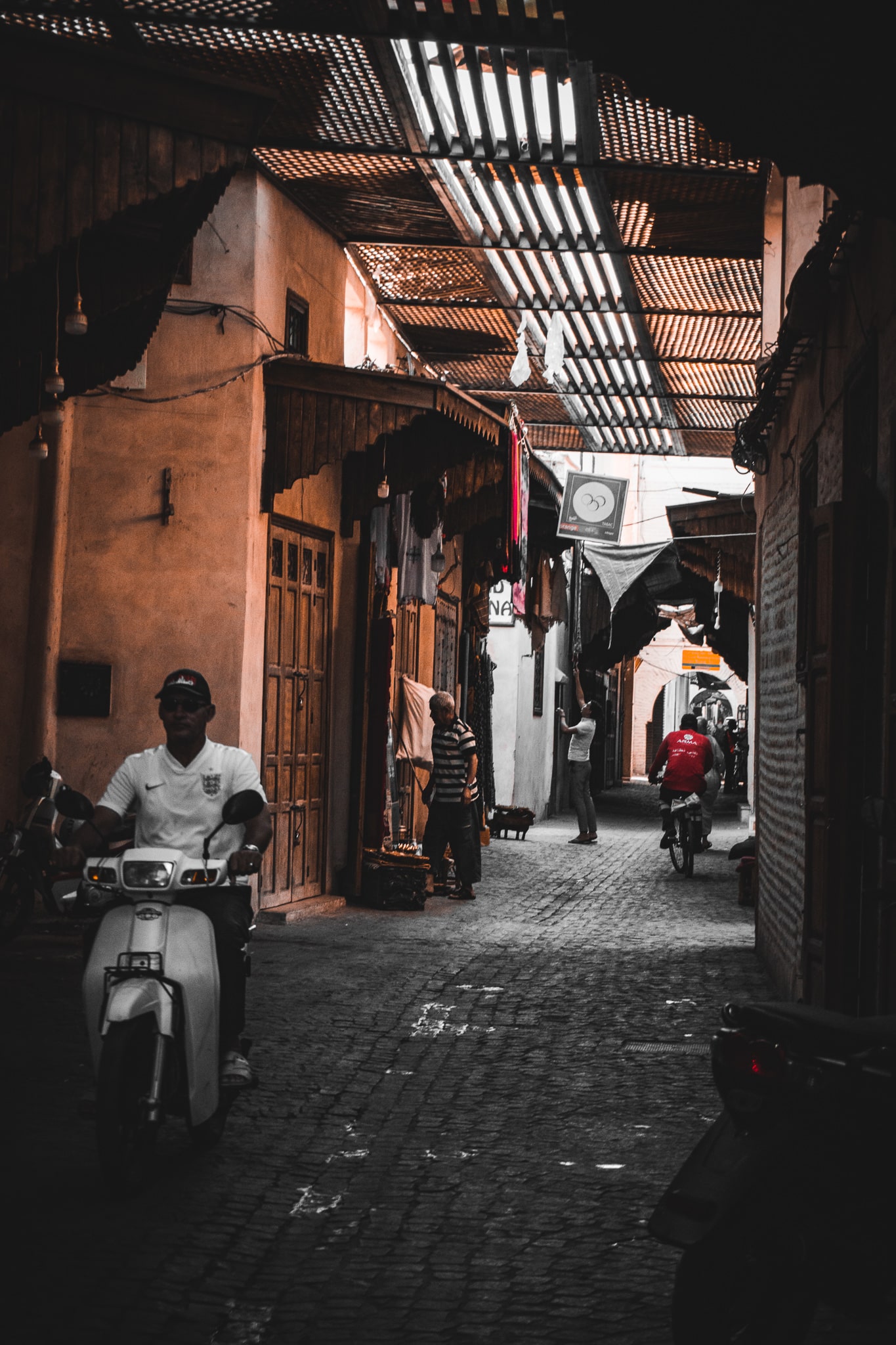 Scooters moving through a narrow covered alley in Marrakech