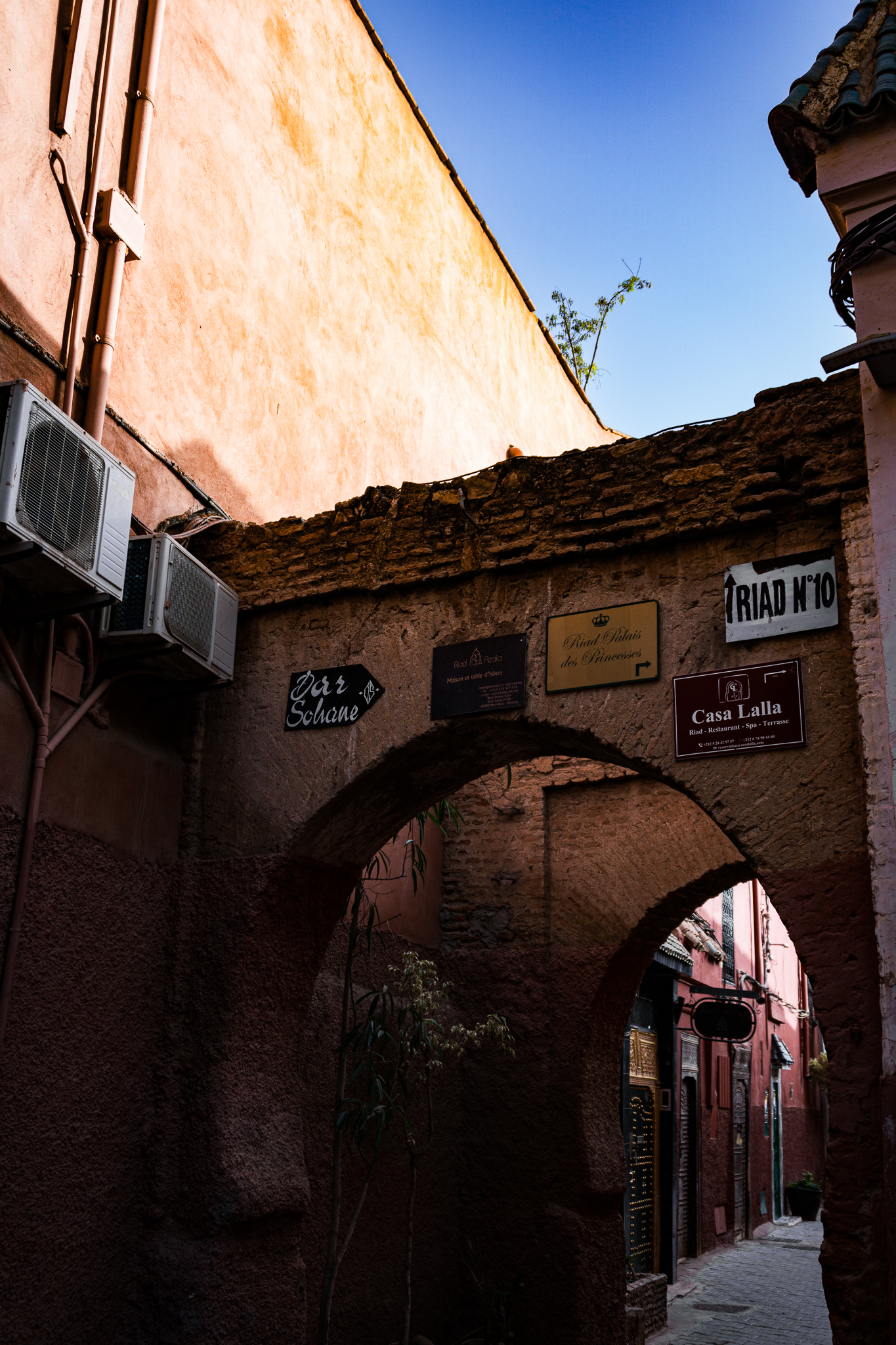 Hospitality signs for riads and guesthouses in a narrow Marrakech medina alley