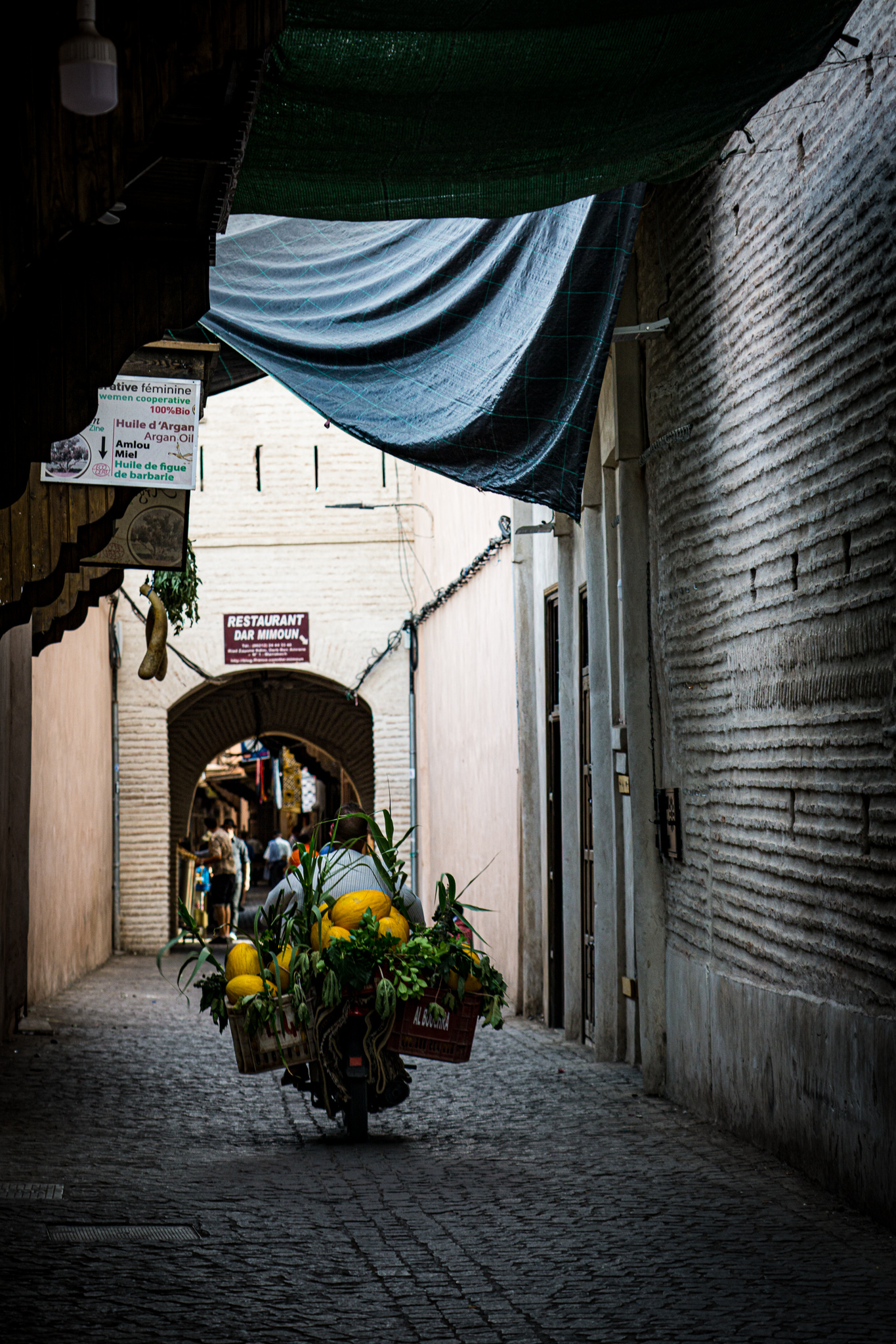 Motorbike carrying produce through a shaded alley in Marrakech medina
