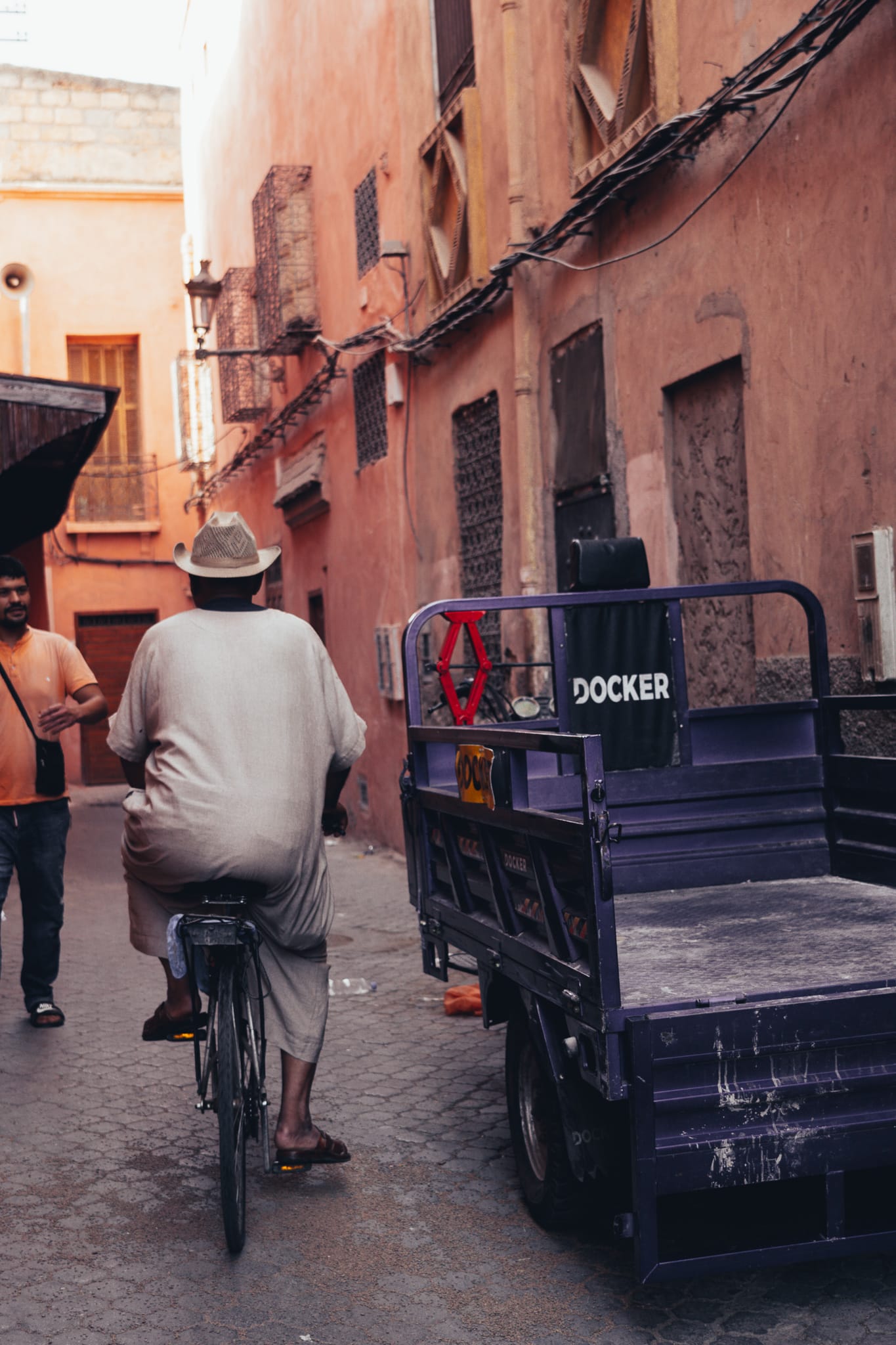 Bicycle rider and cargo tricycle in a narrow alley of Marrakech medina