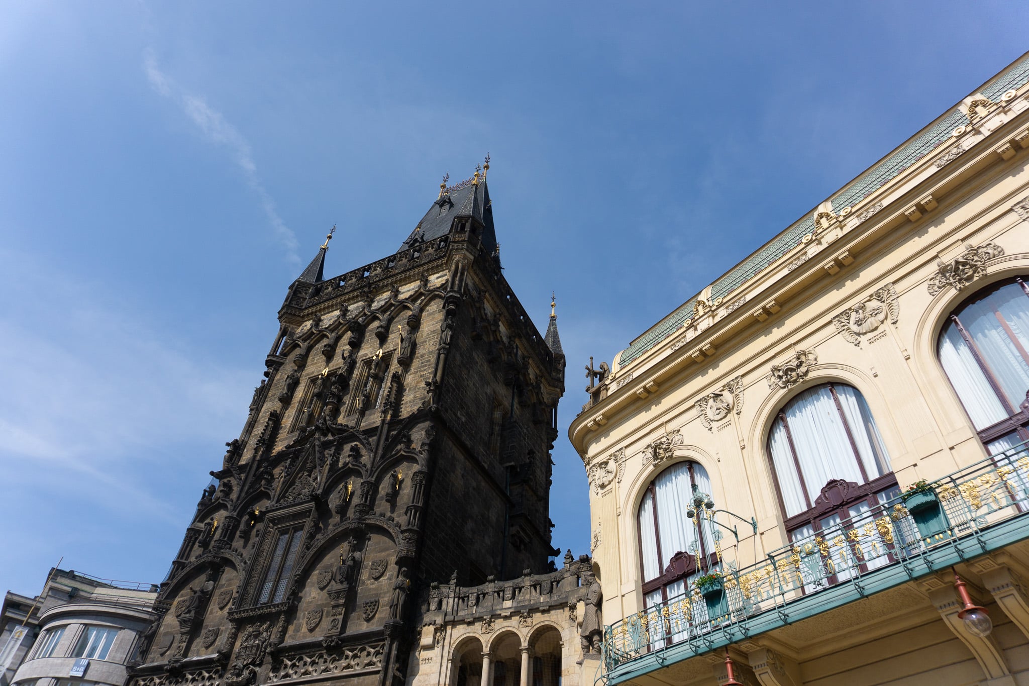 Low-angle view of adjacent Gothic and Art Nouveau buildings in Prague’s historic center.
