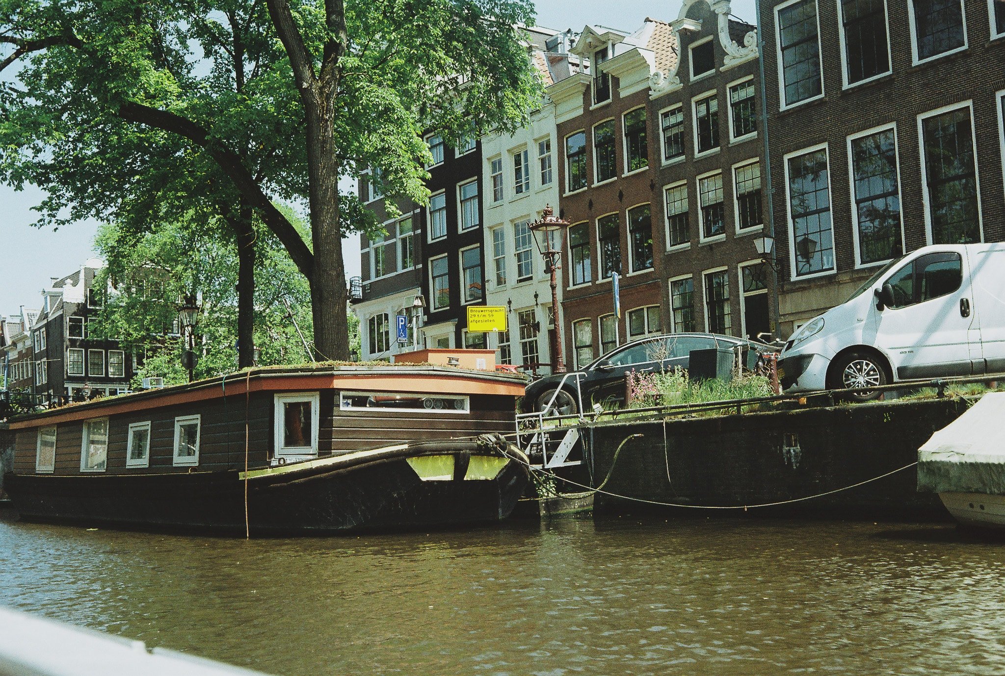Brouwersgracht in Amsterdam with canal houses, moored boats, trees, and canal-side street signage