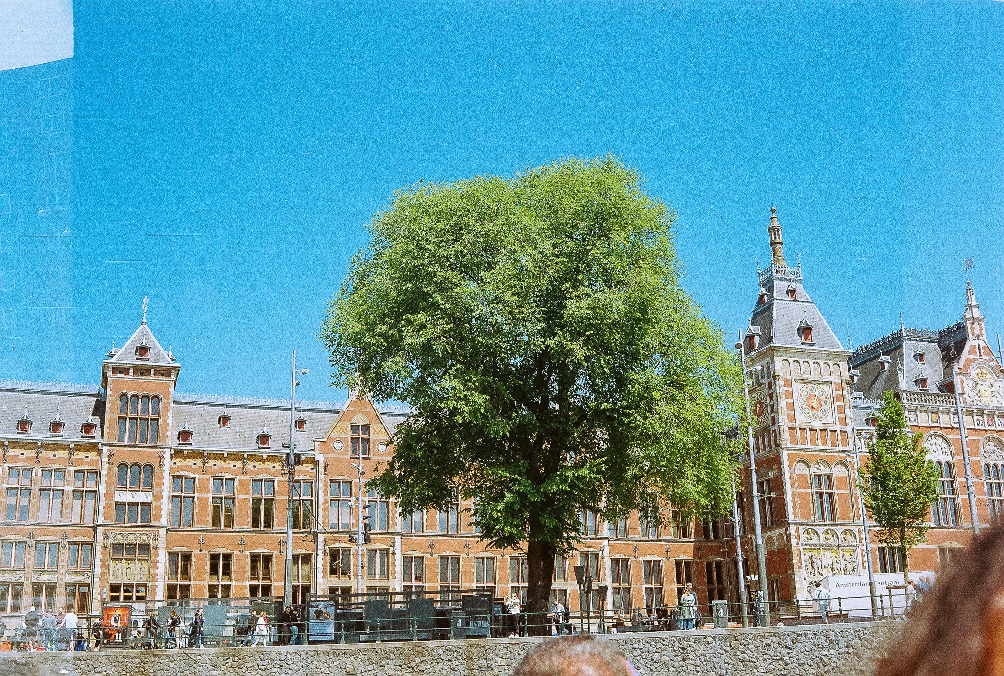 Amsterdam Centraal station viewed from the waterfront promenade with historic facade and pedestrians