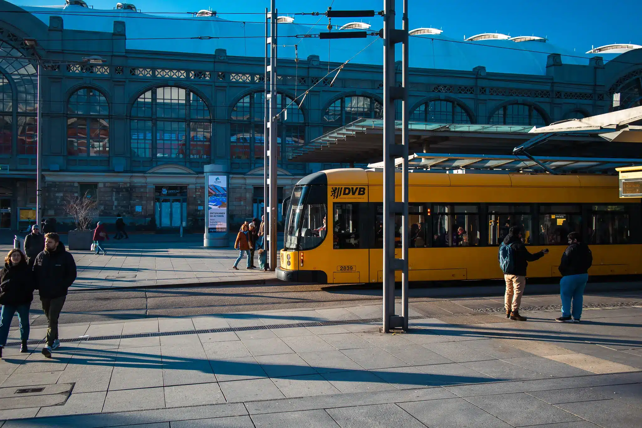 DVB tram stopped at a platform in front of large historic building in Dresden