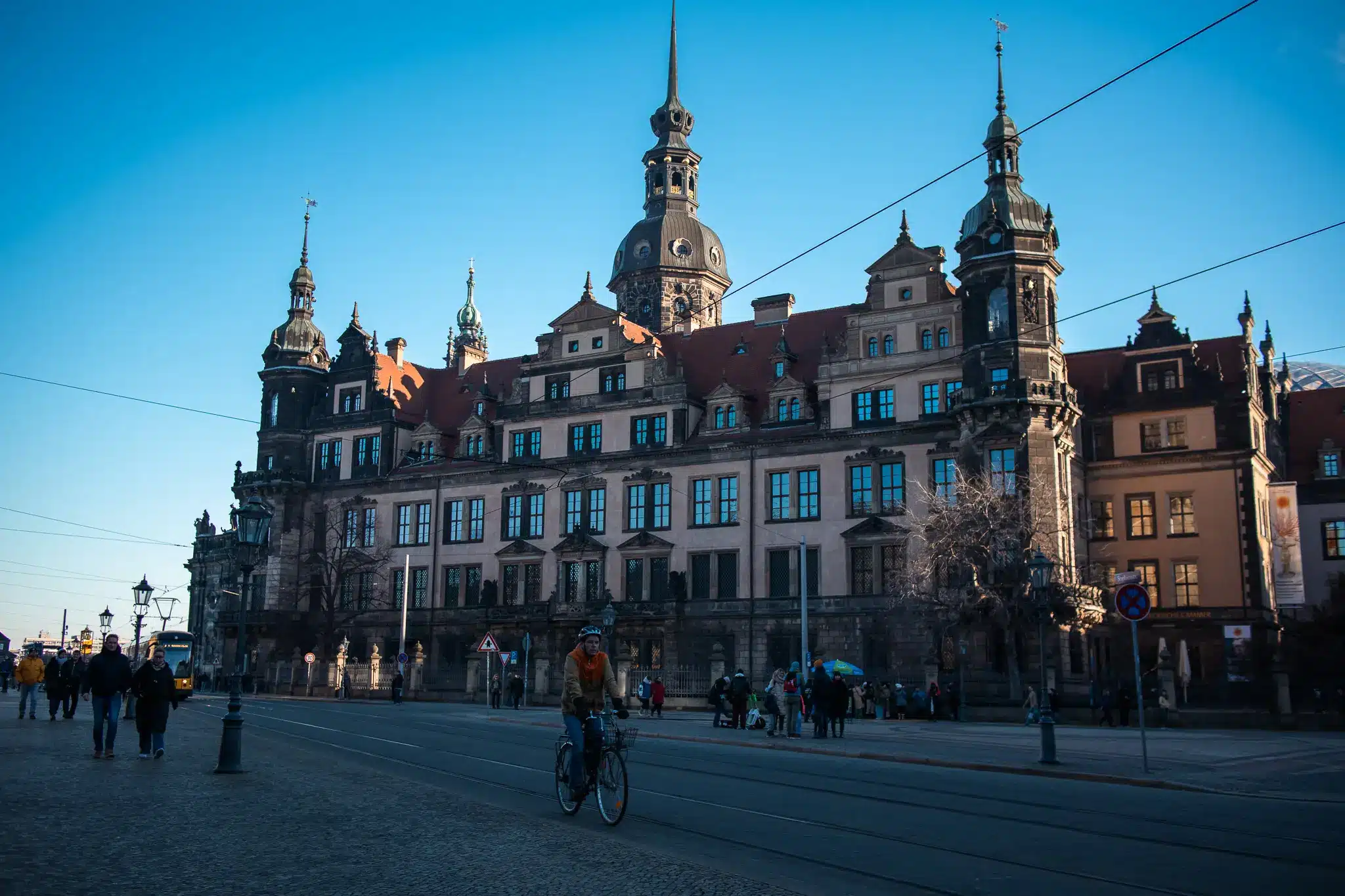 Cyclist near tram tracks in front of large historic Dresden building with towers