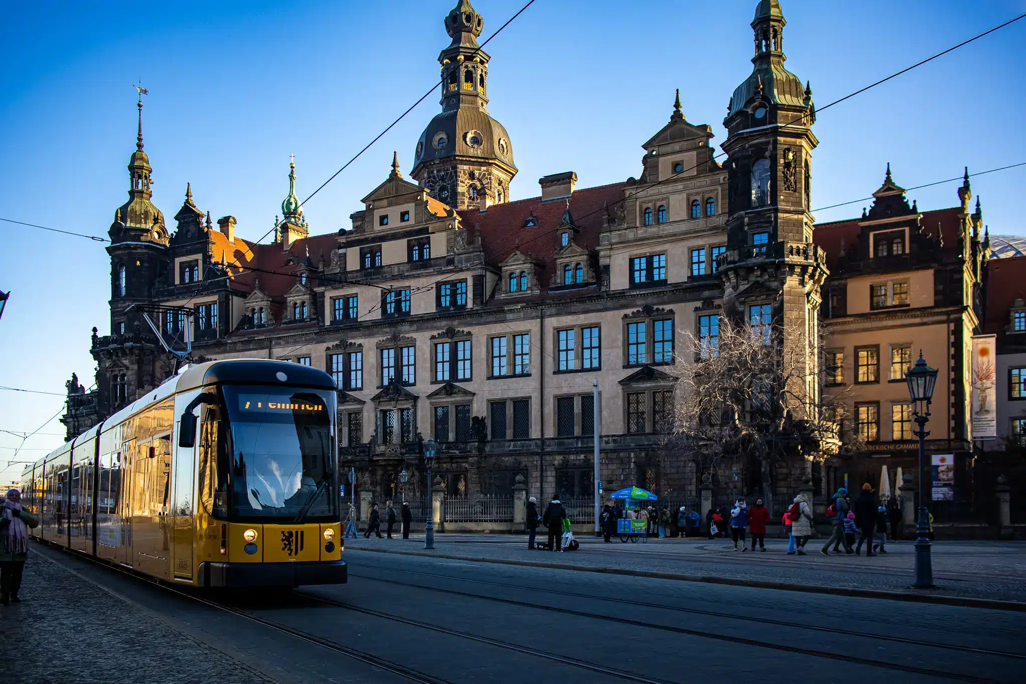 Yellow tram, street vendor umbrella, and grand historic building in Dresden city center