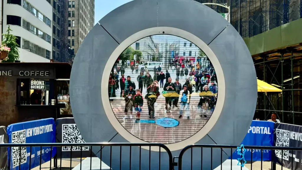 New York City Portal installation in Manhattan with circular live screen, branded fencing, QR codes, barriers, and surrounding street activity.
