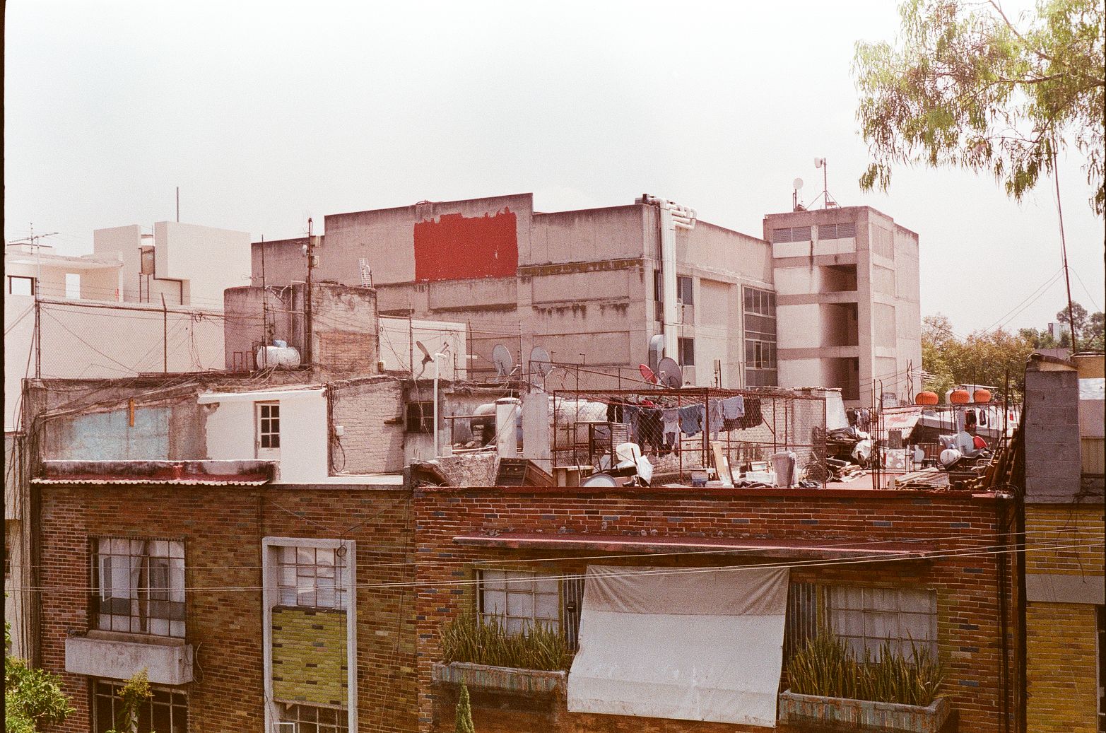Dense Mexico City rooftops with water tanks, antennas, satellite dishes, and laundry lines