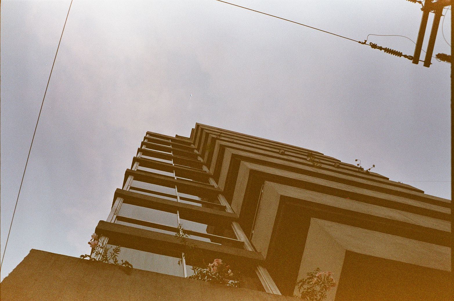 Modern apartment building in Mexico City with stacked balconies and overhead utility wires