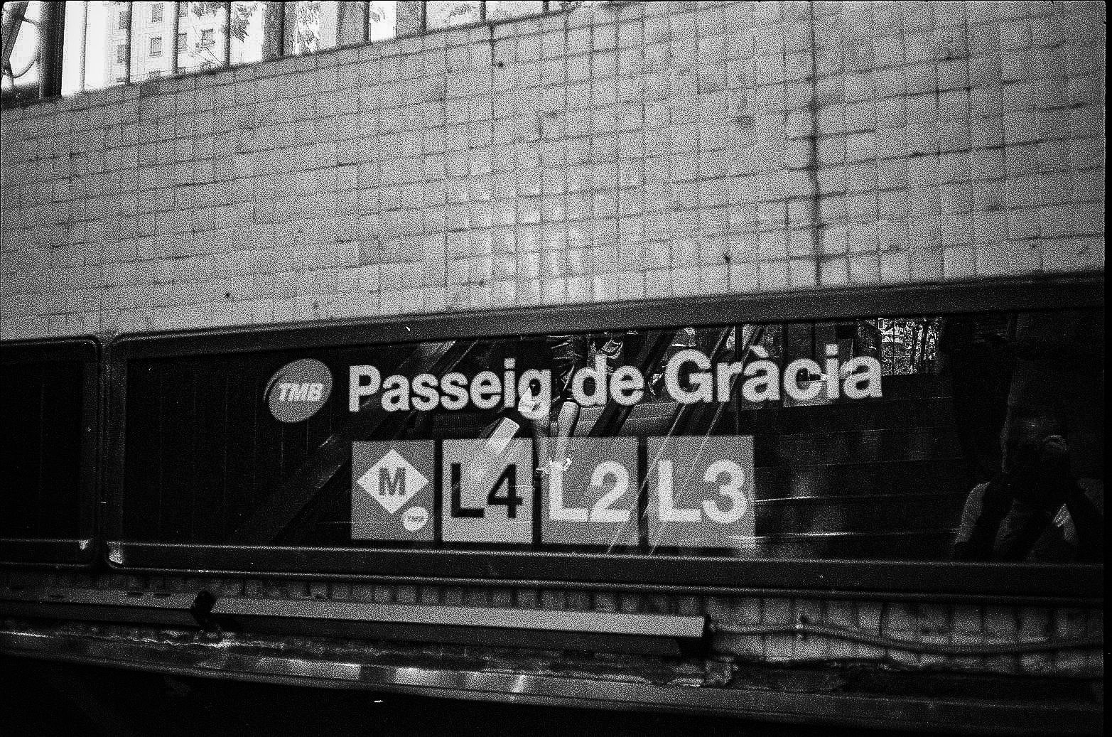Barcelona metro sign for Passeig de Gracia with TMB logo and line markers L4, L2, and L3 in a tiled station setting.