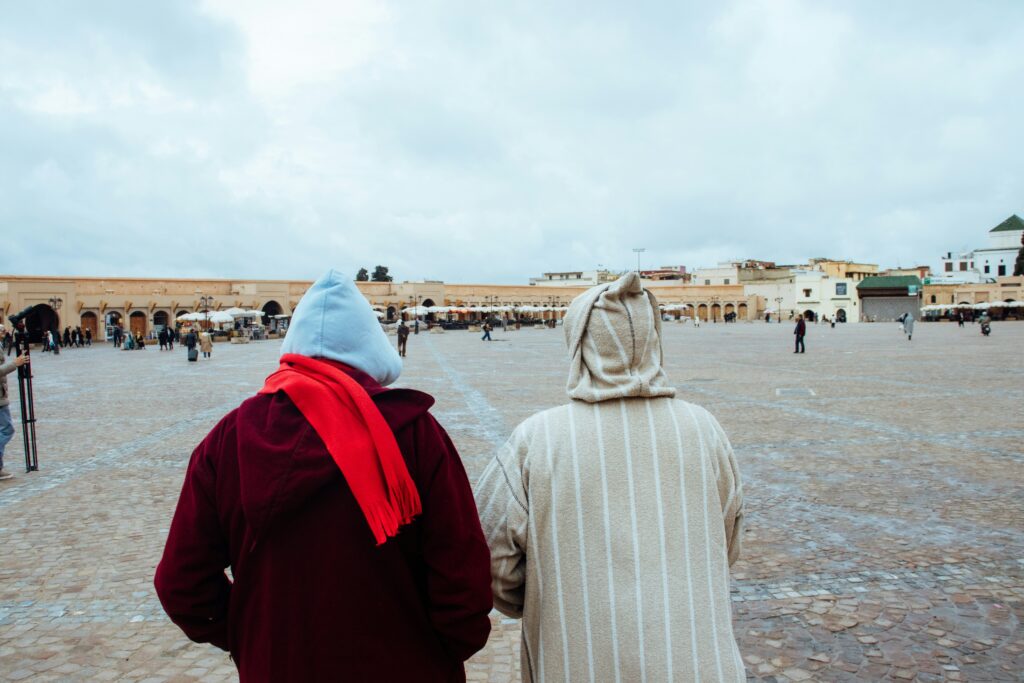 Two people in traditional clothing walk in a square