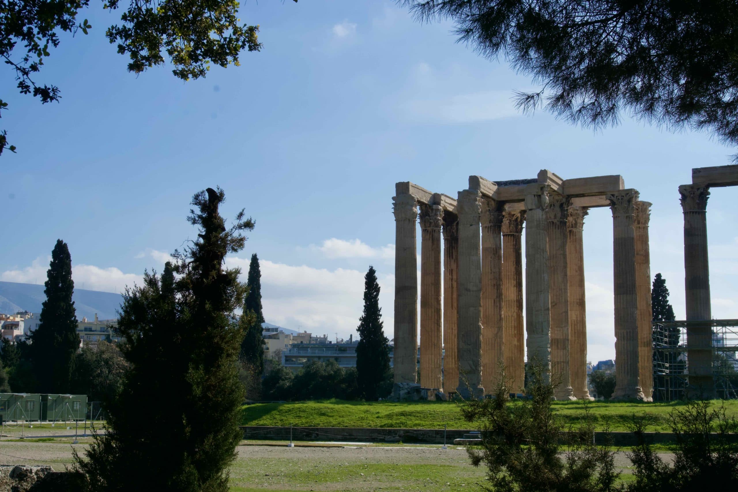 Ancient columns and ruins in Athens with scaffolding and modern buildings beyond