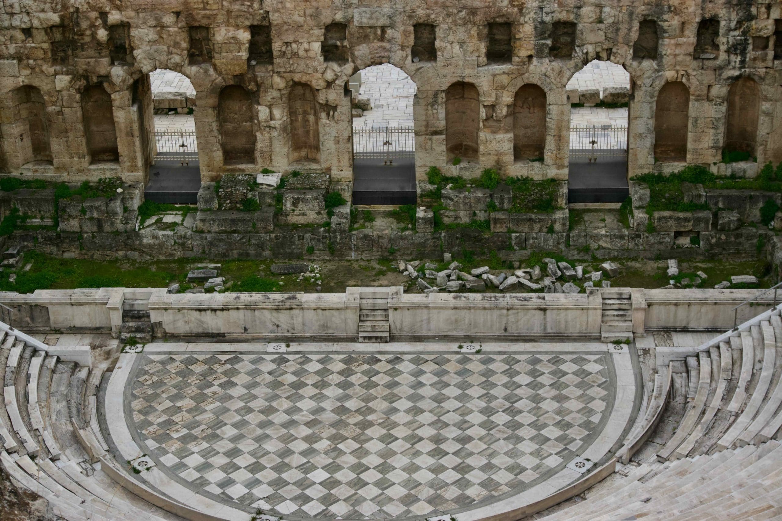 Weathered ancient theater stage wall and curved seating at an archaeological site in Athens