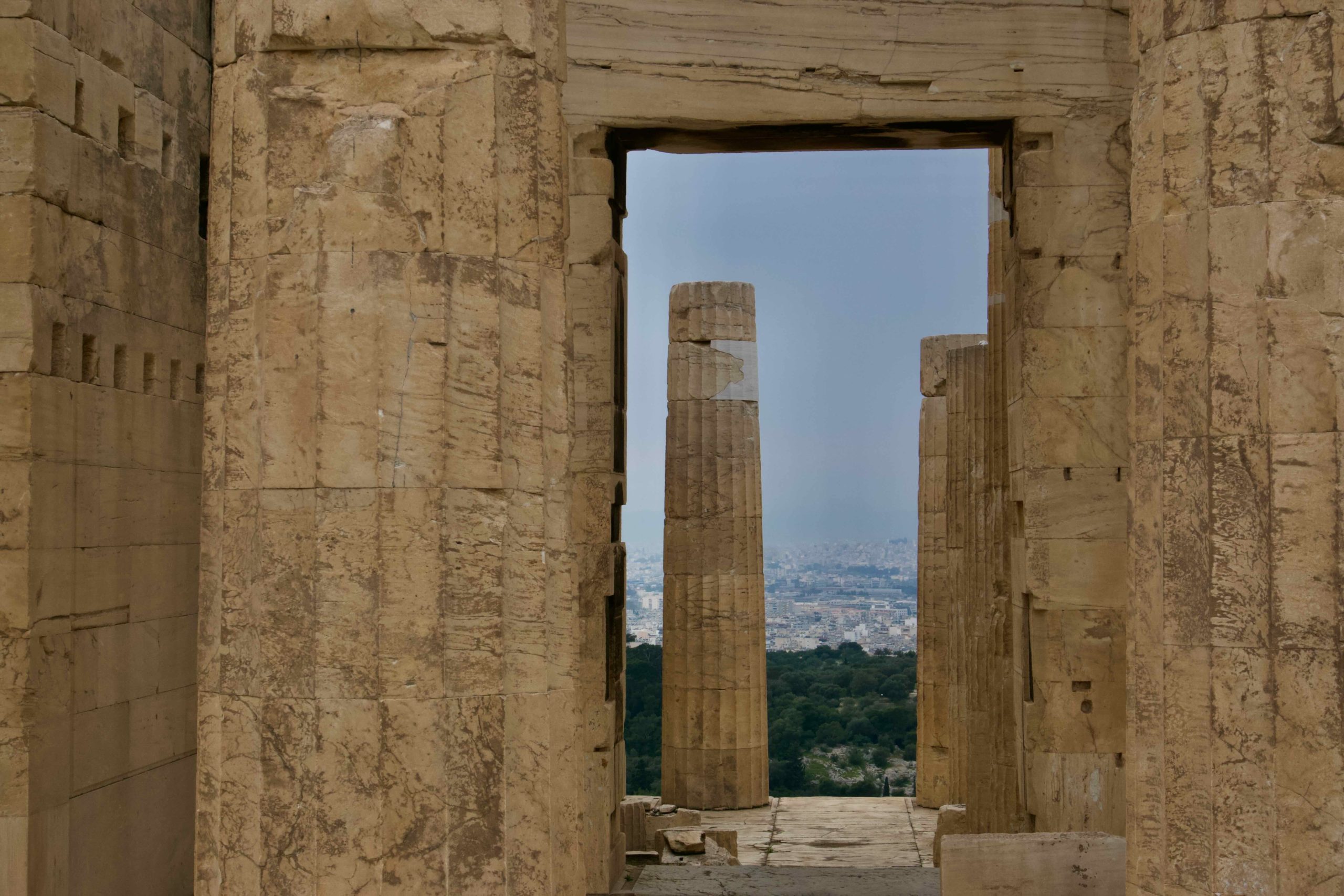Ancient stone doorway opening toward the modern cityscape of Athens