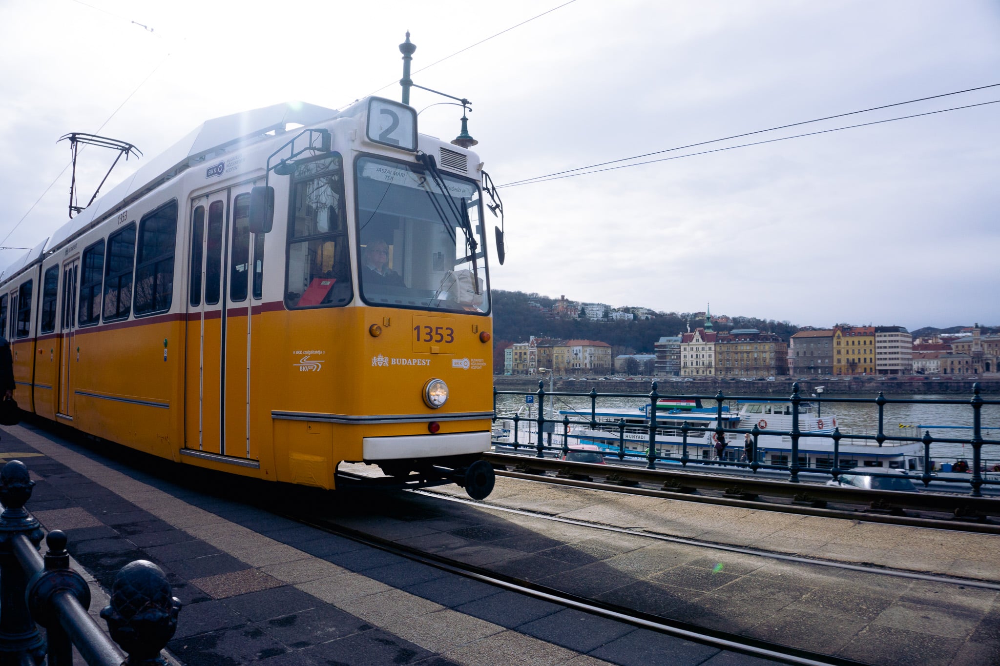 Yellow Budapest tram line 2 running beside the Danube embankment with riverside buildings in the background