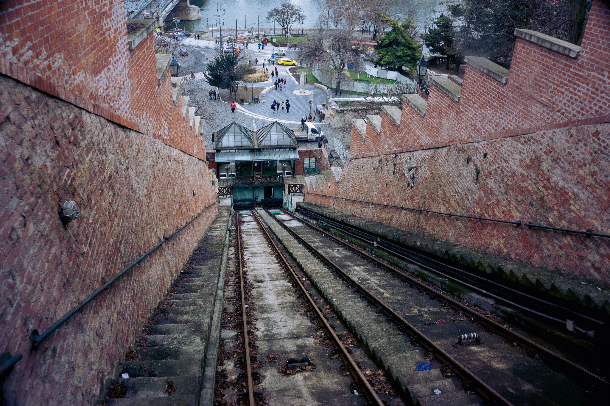 Steep funicular or incline tracks descending toward a waterfront plaza in Budapest