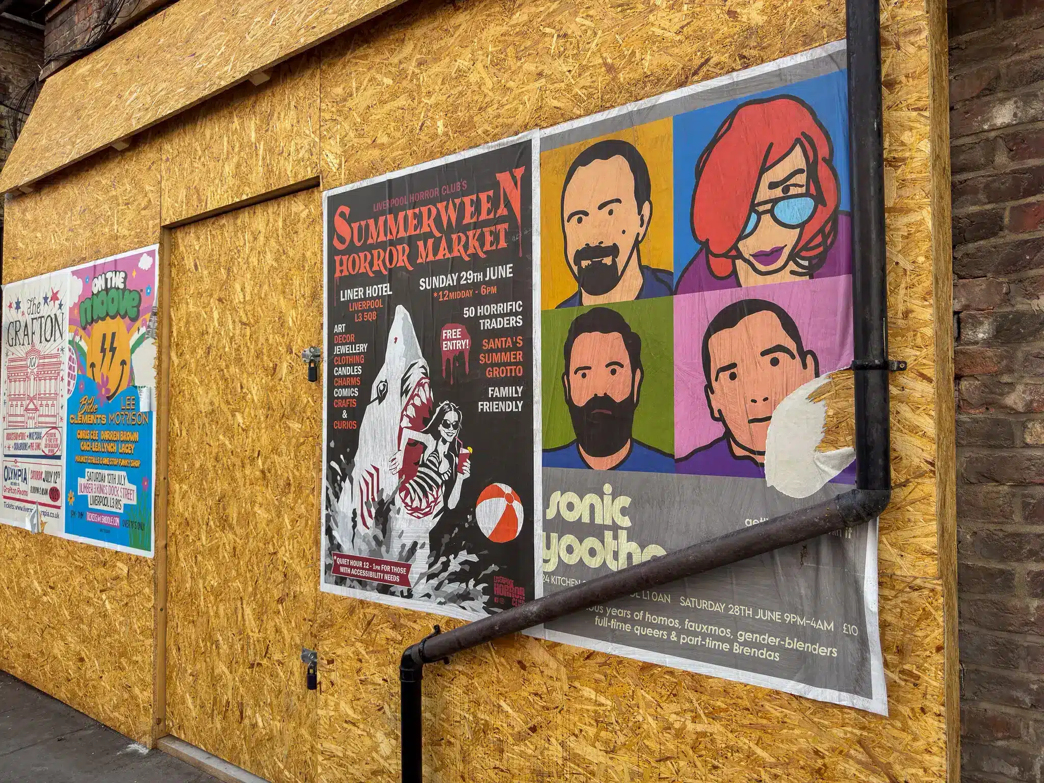 Boarded wall in Liverpool covered with posters for horror market and club events.