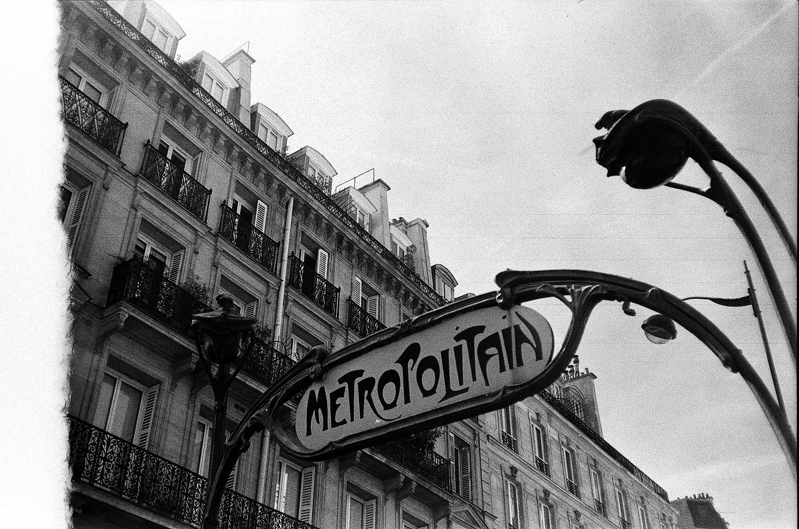 Paris Métro entrance sign reading Metropolitain in front of a Haussmann-style building