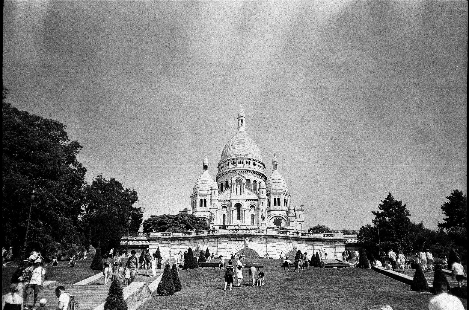 Wide view of Sacré-Cœur Basilica with park foreground and people in Paris