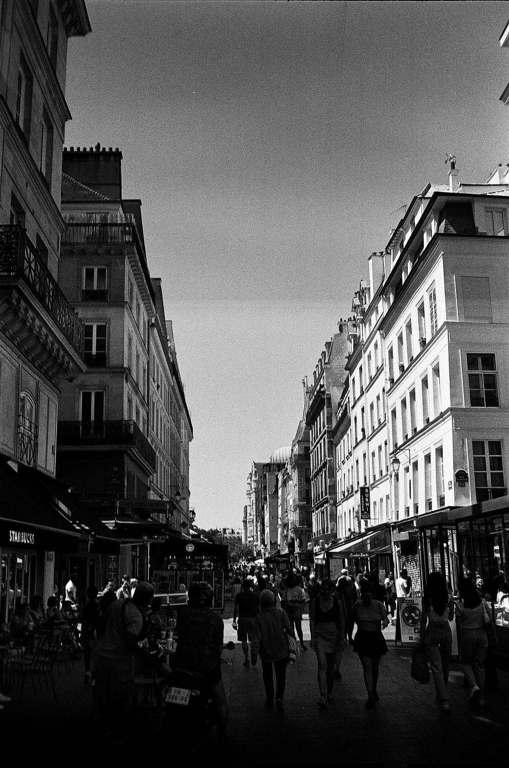 Pedestrian shopping street in Paris with Starbucks awning and other storefront signs