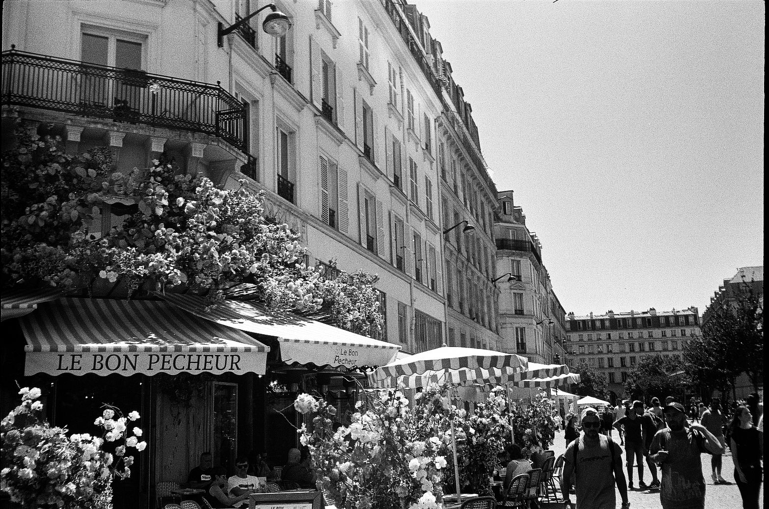 Paris café terrace with striped awnings and outdoor seating on a pedestrian-heavy street
